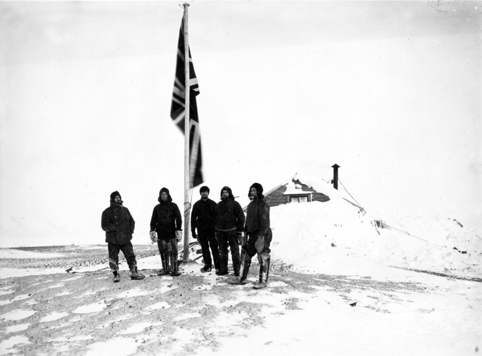 Members of Borchgrevink's expedition standing by the flag. From the left Klovstad, Colbeck, Evans, Fougner and Hanson.