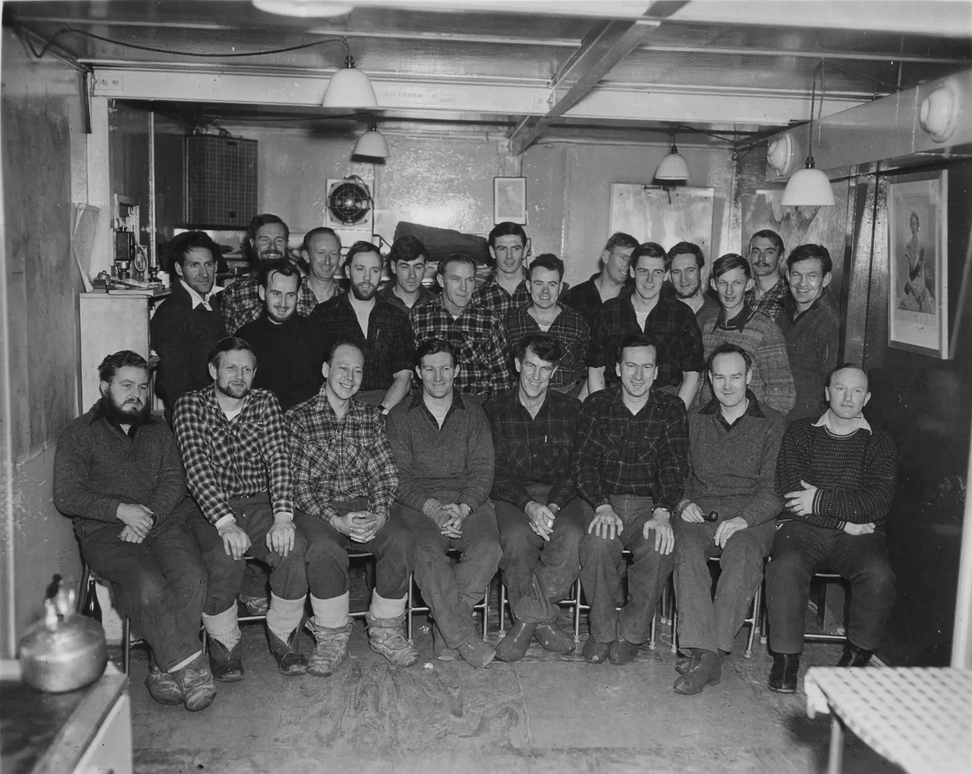 The wintering party at Scott Base, 1957. Back row from left: Wally Tarr, Ted Gawn, Peter Macdonald, Roy Carlyon, Murray Douglas, Richard Brooke, Bill Cranfield. Middle row: Jim Bates, Herbie Orr, Neil Sandford, Harry Ayres, Selwyn Bucknell, Guyon Warren, Peter Mulgrew, Murray Ellis. Front row: Vern Gerard, Bernie Gunn, Ron Balham, Bob Miller, Ed Hillary, Trevor Hatherton, George Marsh, John Claydon.