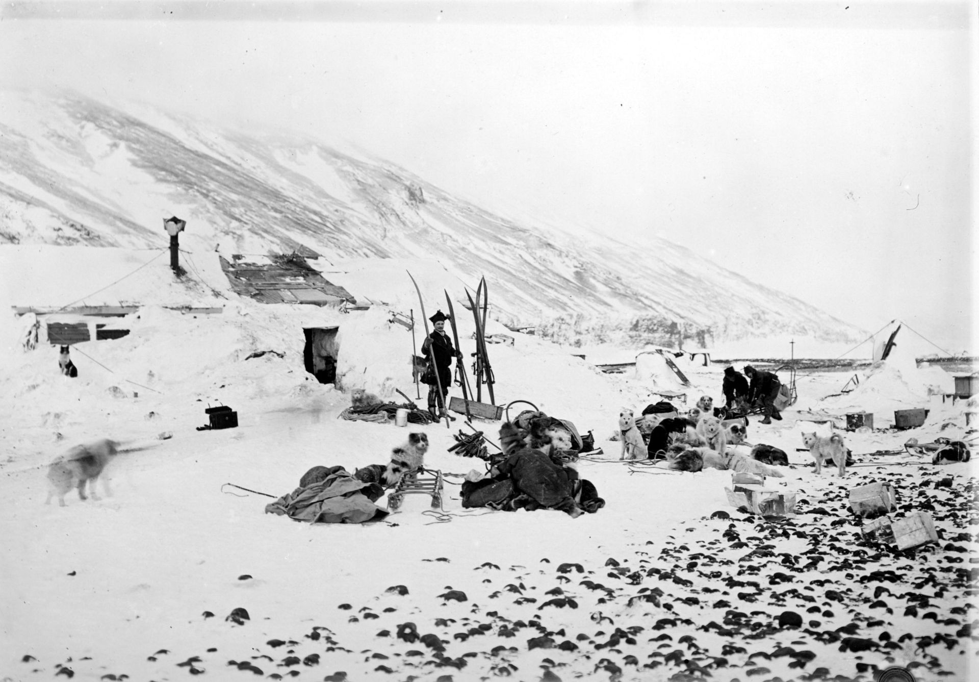 The huts near the end of winter 1899 with Savio by the skis and Must and Evans in the background.