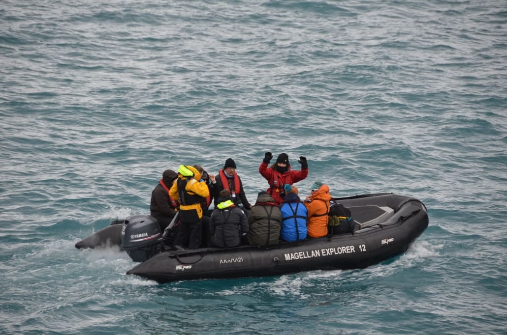 Inspiring Explorer Tegan Allpress waving from a zodiac while cruising Elsehul Bay Antarctic Heritage Trust South Georgia Inspiring Explorers Expedition Magellan Explorer Antarctica21