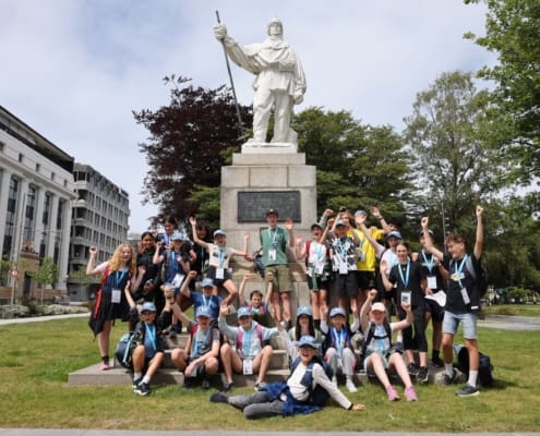 A group of young people standing around a memorial statue of an explorer.