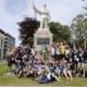 A group of young people standing around a memorial statue of an explorer.