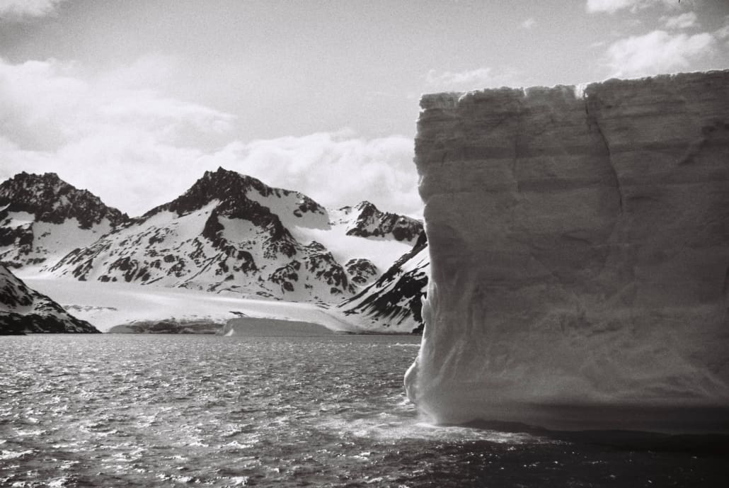 A large iceberg and snowy mountains.