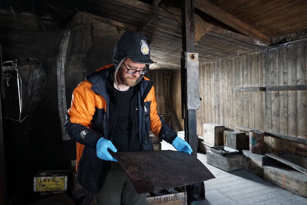 2021-22 Scott's 'Discovery' hut, work task, AHT's Conor Tulloch with blubber stove top. ©AHT/Conor Tulloch